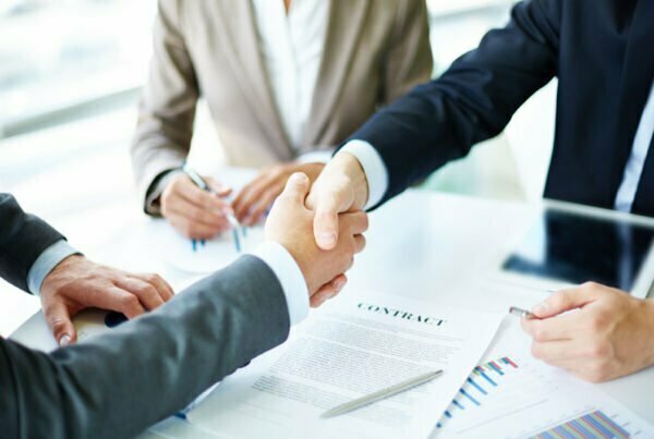 A group of businesspeople shaking hands with a lawyer in front of a skyline of Istanbul.